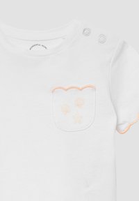 Weißes Babyschlafshirt mit Pfirsichfarbener Einfassung, gewellter Tasche mit Muschel- und Seesternmotiven sowie zwei Druckknöpfen an der Schulter.