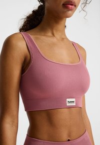 Rosa geribbelde crop top met brede banden, voorzien van een textuur ontwerp en een klein logo label aan de onderkant. Gladde, strakke silhoutte.