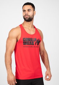Rode mouwloze tanktop met zwarte "GORILLA WEAR" graphic en tekst "UNITED STATES OF AMERICA". Gemaakt van glad, rekbaar stof.