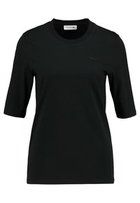 Černé krátké tričko s krátkým rukávem vyrobené z bavlny, s kulatým výstřihem a malým tonálním logem Lacoste na hrudi. Hladká struktura a klasický střih.