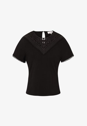 Schwarzes Kurzarmoberteil mit einem Spitzenbesatz am Ausschnitt, der ein dekoratives Muster und Pomponbesatz an den Ärmeln aufweist. Mit einem Reißverschlussdetail auf der Rückseite.