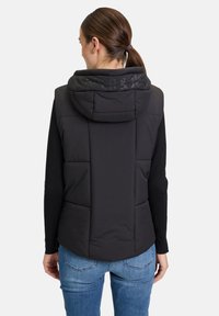 Schwarze gepolsterte Weste mit Kapuze, die eine glatte Textur und elastische Akzente aufweist. Die Rückansicht zeigt große Taschen und Nähdetails.