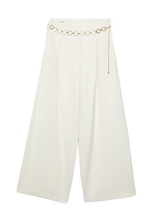 Osoba ubrana w kremowe spodnie o szerokich nogawkach z zakładkami, złoty łańcuchowy pasek z okrągłymi ogniwami oraz czarny krótki top.