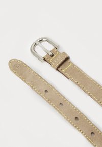 Ceinture en velours beige avec des coutures jaunes et une boucle en métal. Elle présente une texture lisse avec plusieurs trous pour un ajustement personnalisé.