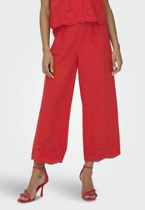Pantaloni larghi rossi con dettagli in eyelet all'orlo, abbinati a tacchi a spillo rossi. Tessuto liscio con vestibilità comoda.