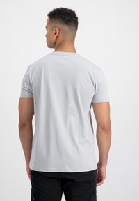 Svetlo siva kratkolesna majica iz mehkega bombaža. Ima klasičen okrogel izrez in sproščen kroj, brez vidnih vzorcev ali okraskov.