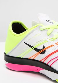 Nike sportovní obuv s bílým síťovaným svrškem a jasně žlutými, růžovými a oranžovými akcenty, černým logem swoosh a růžovou podrážkou.