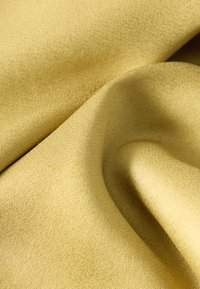 Tessuto giallo morbido e finemente intrecciato con pieghe delicate e una trama liscia visibile nei dettagli ravvicinati.