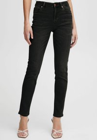 Jeans de denim negro ajustados con una cintura alta y diseño de cinco bolsillos, presentando herrajes en tono cobre y un desvanecimiento sutil.