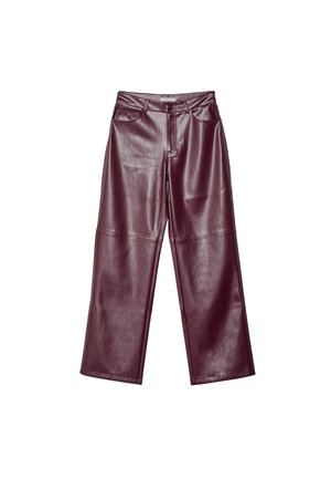 Personne portant un pull gris à épaules dénudées, pantalon en cuir bordeaux taille haute, talons noirs, tenant une grande pochette noire.