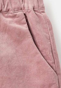 Lodentyg i mjuk rosa med vertikal ribb. Har en elastisk midjeband och sidofickdetalj. Slät textur.