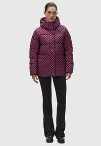 Puffjacka i rosa och svart geometriskt mönster med hög krage och huva. Designad med horisontella quiltade paneler och två sidofickor.