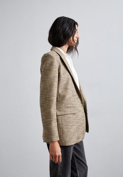 Tanternet plaid blazer med tætsiddende pasform, enkeltknaplukning, notch-lapel og to frontlommer, parret med en hvid bluse og mørke jeans.