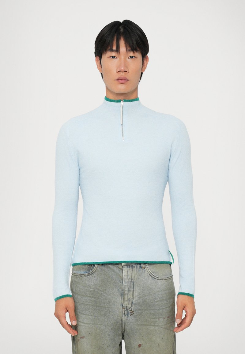 Ljusblå långärmad topp med hög krage och dragkedja, med grön trim vid kragen och fållen. Mjuk textur, figursydd design.