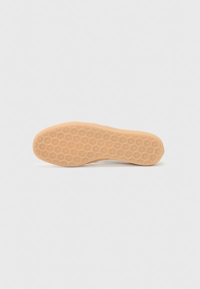 Semelle en caoutchouc avec un motif hexagonal de couleur brun clair. Texture lisse avec un design plat et une légère courbure au niveau du talon.