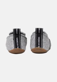 Grijze gevoelde slippers met een gestructureerde afwerking, voorzien van zwarte trekriemen en rubberen zolen. Eenvoudig ontwerp met gestikte details aan de zijkant.