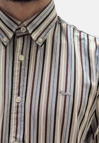 Camicia a righe bianca, marrone e blu, con colletto, bottoni frontali e un logo ricamato sul petto.