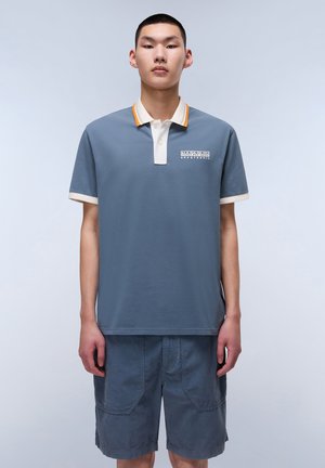 Polo gris en coton avec un col blanc et des accents orange, portant un logo sur la poitrine gauche, associé à un short gris.