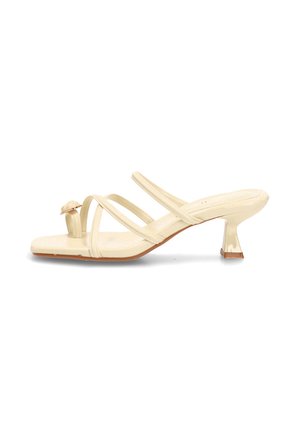 Sandalia beige con punta abierta, tiras finas entrecruzadas, punta cuadrada y tacón corto y curvado.