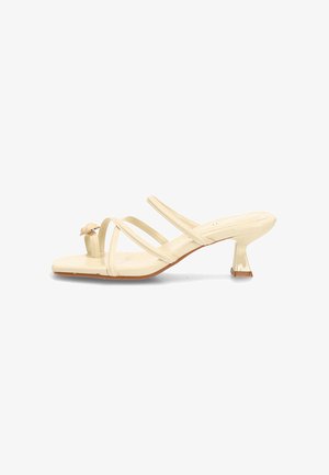 Sandalia beige con punta abierta, tiras finas entrecruzadas, punta cuadrada y tacón corto y curvado.