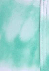 Lichtgroene stof met een tie-dye patroon in verschillende tinten, met een gladde textuur en gestikte randen.