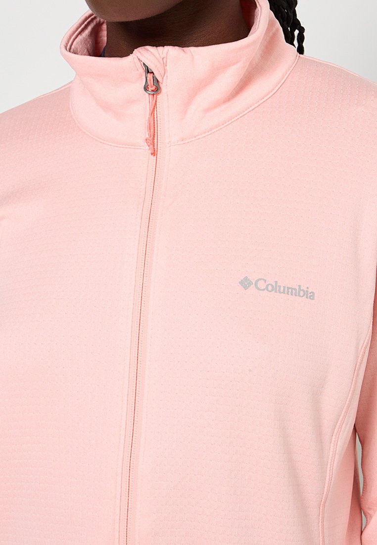 Chaqueta de cremallera color rosa claro hecha de un tejido texturizado con cuello alto; presenta un sutil logo de Columbia en gris en el pecho.