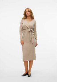 Bežna obleka s dolgimi rokavi in ovitkom, pas na pasu. Gladka tekstura, do kolen in z V-izrezom. Nosijo jo s črnimi balerinkami.