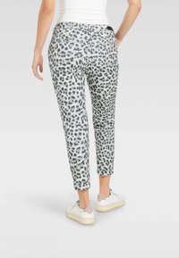 Leopard print pants in gray and black with a tapered fit, featuring back pockets, finished with a smooth texture and ankle-length cut.