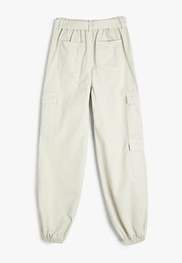 Ljusbeige cargo-byxor med elastisk midja, tapered ben och två sidofickor med fackstängningar, samt två bakfickor.