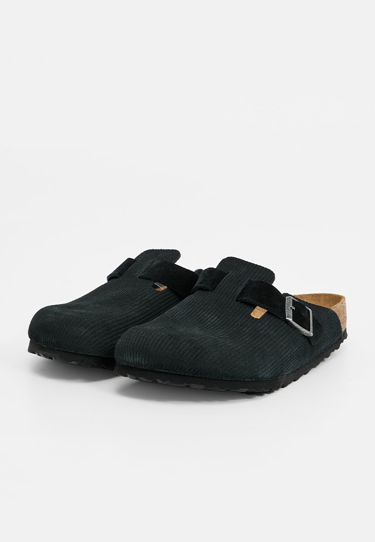 Schwarze Corduroy-Clogs mit einem Korkfußbett, ausgestattet mit einem verstellbaren Riemen und einer Metallschnalle, strukturierter Oberfläche und abgerundetem Zehendesign.