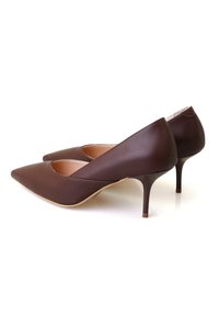 Chaussures à talons hauts en cuir marron avec un bout pointu et un design découpé sur les côtés. Talons aiguilles fins avec une texture lisse.