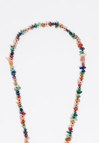 Collar de cuentas multicolores con diversas piedras preciosas en formas irregulares, ensartado con pequeñas cuentas negras entre las piedras.