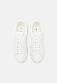 Hvide lædersneakers med en glat overflade, rund tå, flade snørebånd og et subtilt logo på tungen. Minimalistisk design og lav profil.