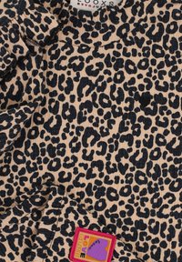 Leeuwenhuidprint stof in beige en zwart, met een kleurenrijke "Love Club" label en een textuur van gerimpelde randen.