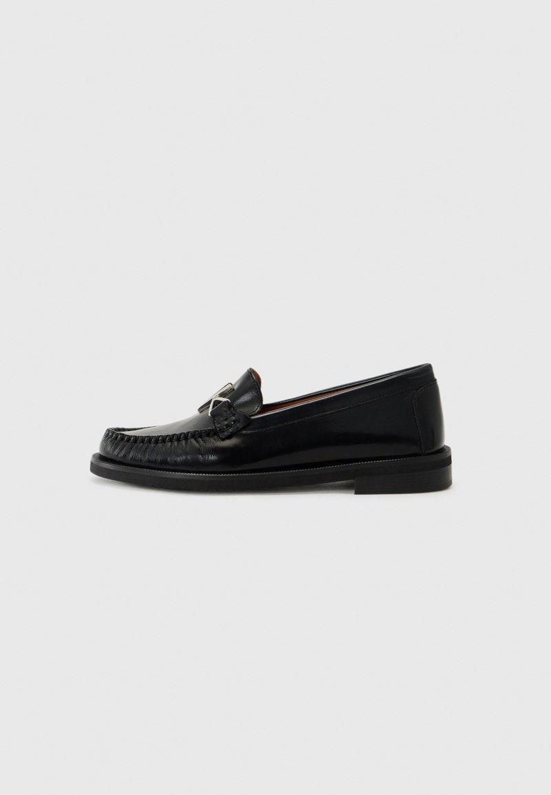 Mustad musta nahast loafers, millel on mokasiinistiilis disain, kaunistatud õmmeldud varba detailiga ja väikese metallaktsendiga küljel. Lamav kummitald.