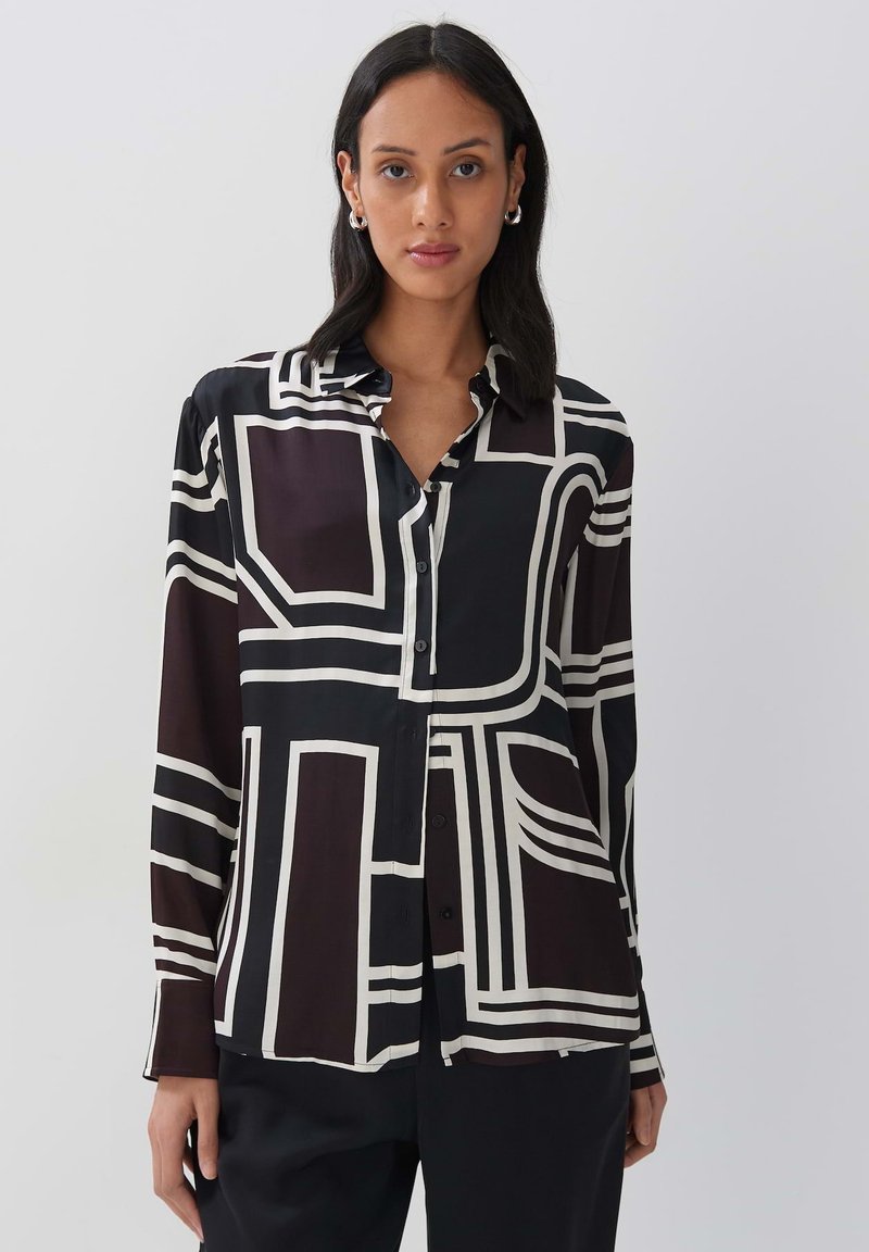 Black and white button-up shirt featuring geometric patterns, long sleeves, and a soft texture. The design contrasts bold lines on a dark background.