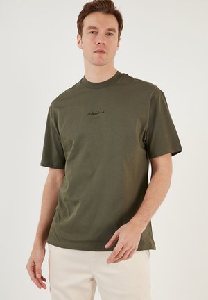 Olive green short-sleeve t-shirt in soft cotton, featuring a round neckline and a small black embroidered logo on the chest.