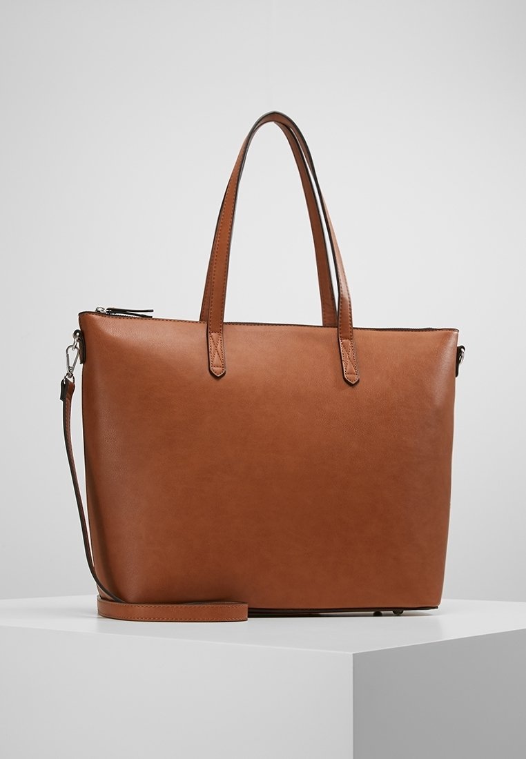 Brązowa skórzana torba typu tote z podwójnymi uchwytami u góry i odpinanym paskiem na ramię. Gładka tekstura, minimalistyczny design i zamek błyskawiczny na górze.