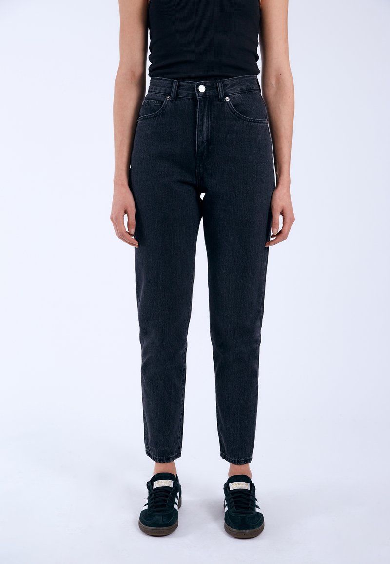 Högmidjade svarta denimjeans med rak passform, femficksdesign och synliga sömmar, kombinerade med svarta sneakers.