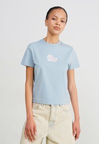 Ljusblå bomulls-t-shirt med rund halsringning, korta ärmar och en rosa snäcka-grafik på bröstet. Slimmad design med en mjuk yta.