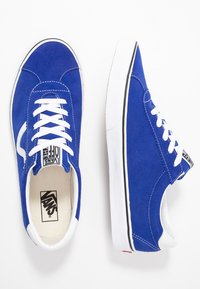 Pari di sneaker Vans in suede blu con lacci bianchi, suole bianche e striscia laterale distintiva, mostrato da viste superiori e laterali.