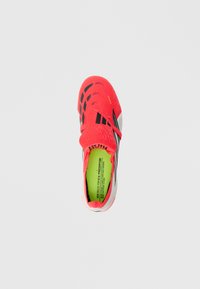 Φωτεινό κόκκινο και μαύρο ποδοσφαιρικό παπούτσι με φώσφορο πράσινο εσωτερικό πέλμα, "EST. 1994" στη γλώσσα και την επωνυμία "PREDATOR" στο λουράκι και στο εσωτερικό της σόλας.