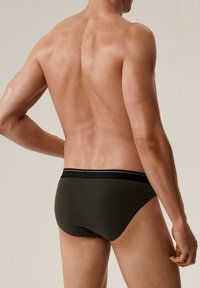 Ciemnozielone bawełniane slipy męskie z czarnym elastycznym paskiem w talii z cienką białą paskiem. Gładka tekstura, dopasowany krój.