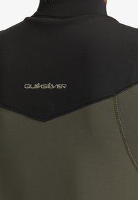 En våtdräkt med en svart överdel och olivgrön underdel. Slät yta med platta sömmar och Quiksilver-logotyp på ryggen.