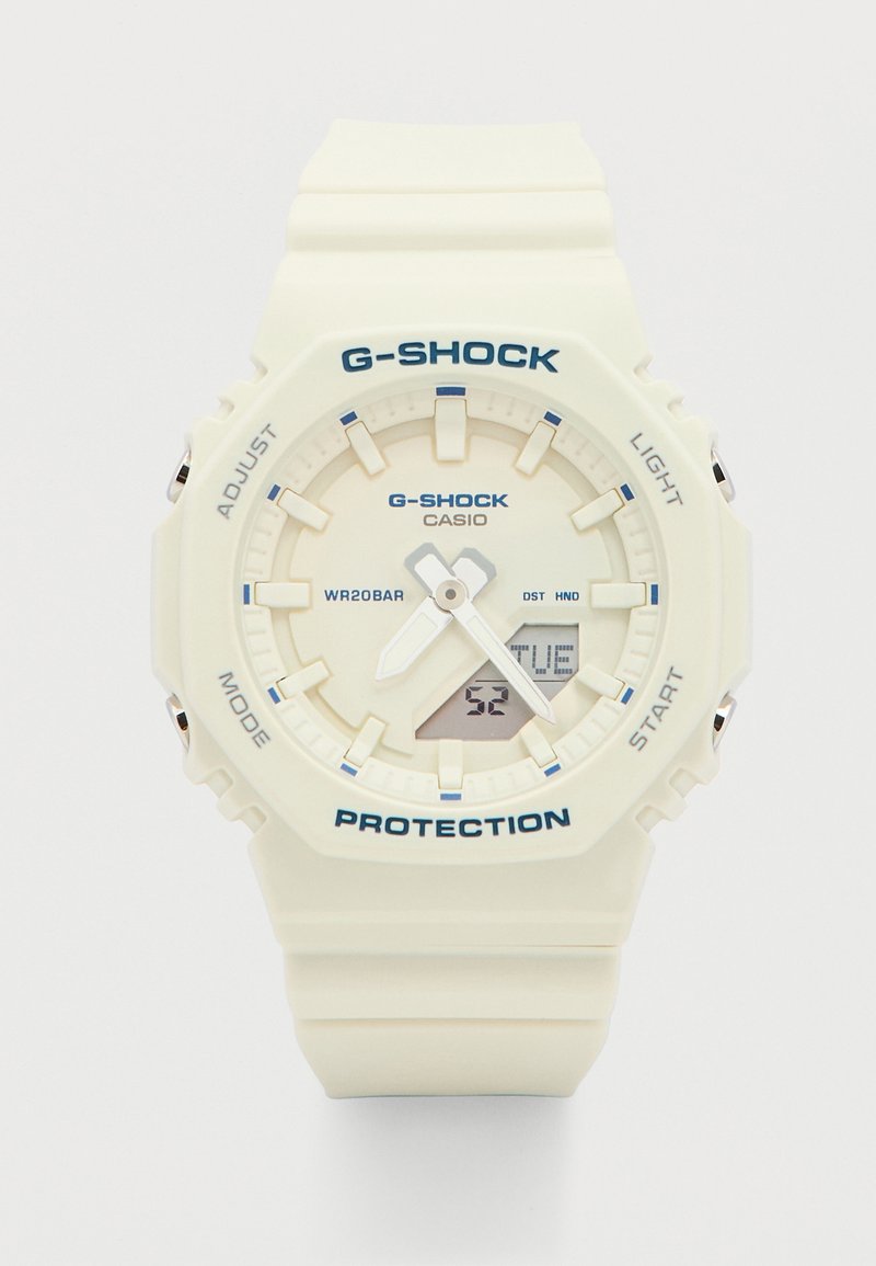 Λευκό ρολόι χειρός Casio G-Shock με αναλογικά δείκτες, ψηφιακή εμφάνιση ημερομηνίας που δείχνει "ΤΡΙ", και προστατευτικό λουράκι από ρητίνη.