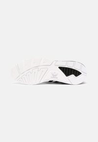 Melnā un baltā krāsā sporta apavu zole ar teksturētu gumijas virsmu, kurai ir ģeometriskas formas un Adidas logo sānos.