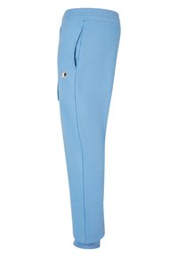 Ljusblåa mjukisbyxor i mjukt, ventilerande tyg. Har en ribbad midja, sidofickor och en svart logotyp i accent.