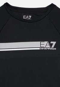 T-shirt de sport noir avec une texture lisse, un col rond et une bande imprimée blanche avec un motif en maille et un détail de logo à l'avant.