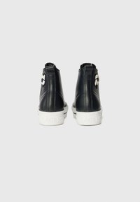 Black leather high-top sneakers with white rubber soles, featuring a circular logo accent and pull tabs on the heel.