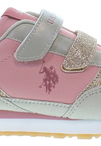 Rosa och grå sportskor med en kardborreband, glittrande detaljer, mocka-textur och en logotyp med två polo-spelare.